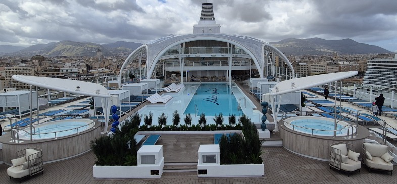 Aan een kant van het openluchtzwembad op De Mein Schiff Relax staan twee bubbelbaden. Rondom het zwembad staan ligbedden, zitjes, cabana's, bars en bistro's. © Nico van Dijk / Decruisegids.nl